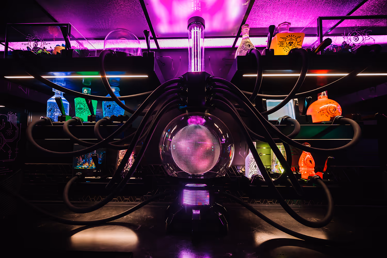 Futuristic lab setup with glowing orb connected by multiple tubes under purple lighting. DataMosh bar at Meow Wolf Las Vegas