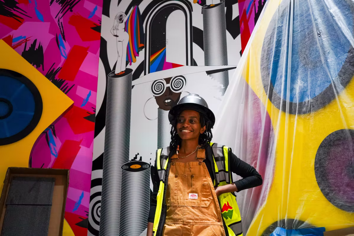 An artist standing in front of a mural at Meow Wolf Houston