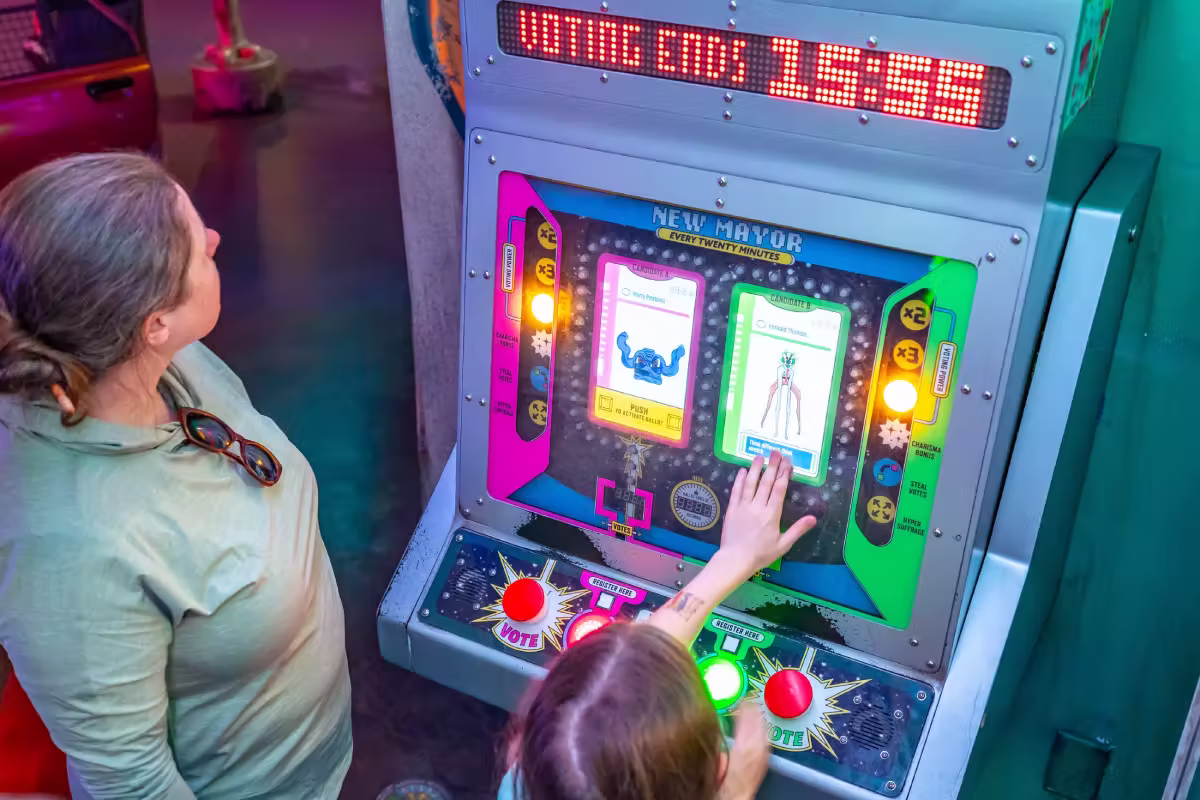 An adult and chid looking at an interactive screen machine at Meow Wolf Denver