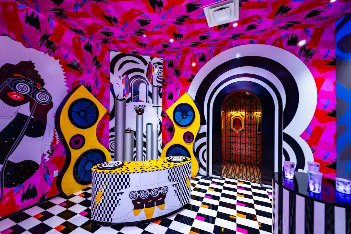 brightly colored space with pink walls and large murals of a face with spiral eyes